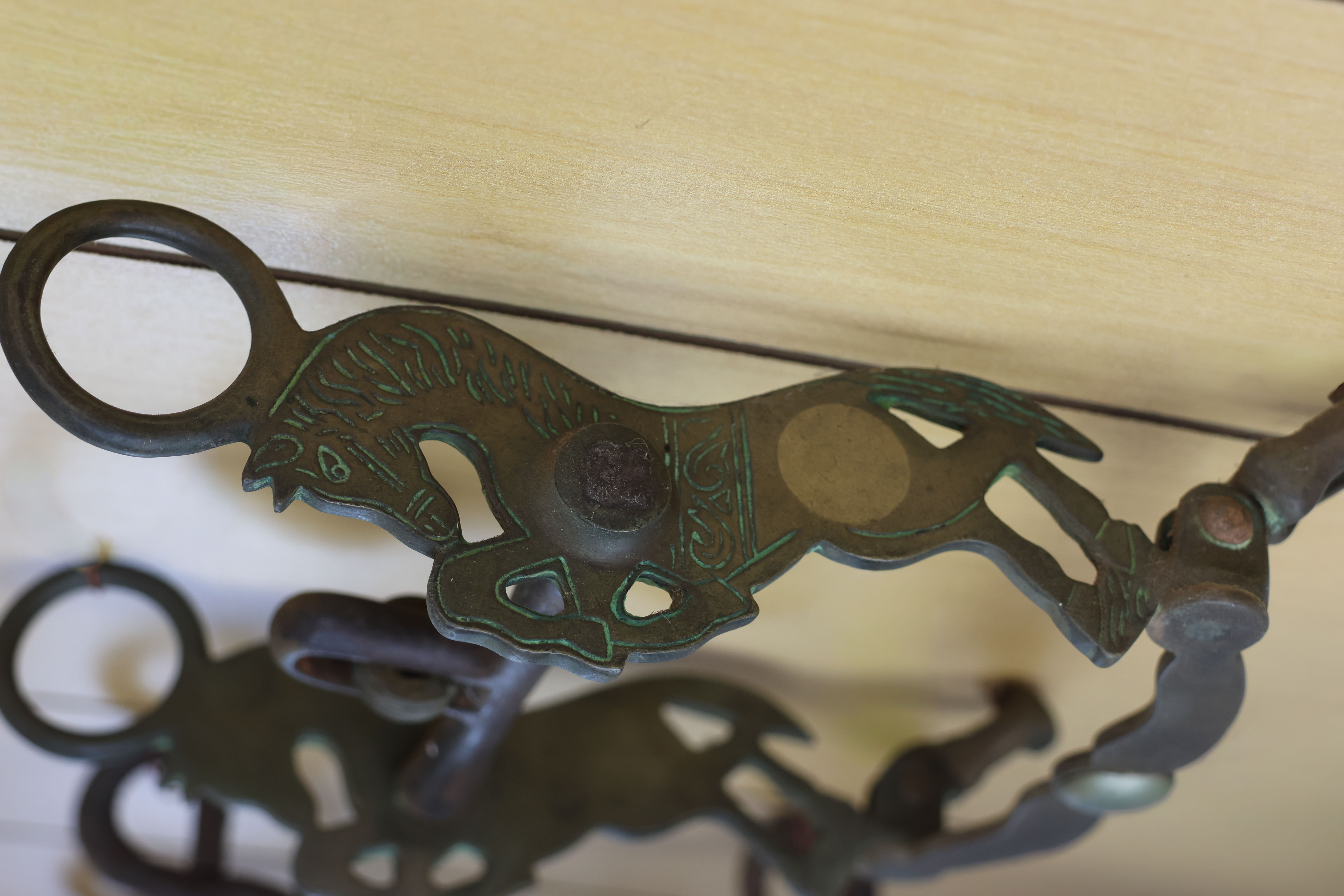 Decorative metal horse bit featuring a carved horse-shaped shank with engraved line detailing and circular metal accents.